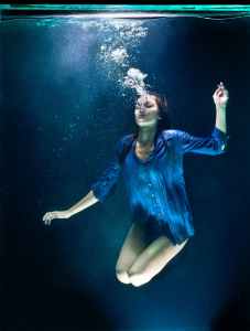 A young woman exhales under water.