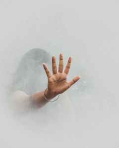 A hand reaches out from fog or smoke.