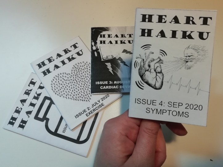 A hand holds a miniature black and white zine. Cover reads "Heart Haiku, Issue 4: Sep 2020, Symptoms" and shows an image of a bearded male head blowing air onto a vibrating heart with a heartbeat trace line coming out of it.