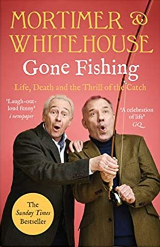 Cover of book: Mortimer and Whitehouse Gone Fishing: Life, Death and the Thrill of the Catch. A salmon-pink background with a photograph of Paul Whitehouse and Bob Mortimer standing side by side. Bob holds a fishing rod and appears to be reeling in a catch. Paul places a guiding hand on the rod and the other hand on Bob's shoulder. Both have eyes and mouths wide open.